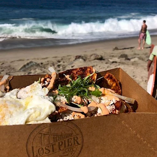 The image shows a box of food, possibly tacos or similar, with a beach scene in the background. The brand "Lost Pier" is visible on the box.