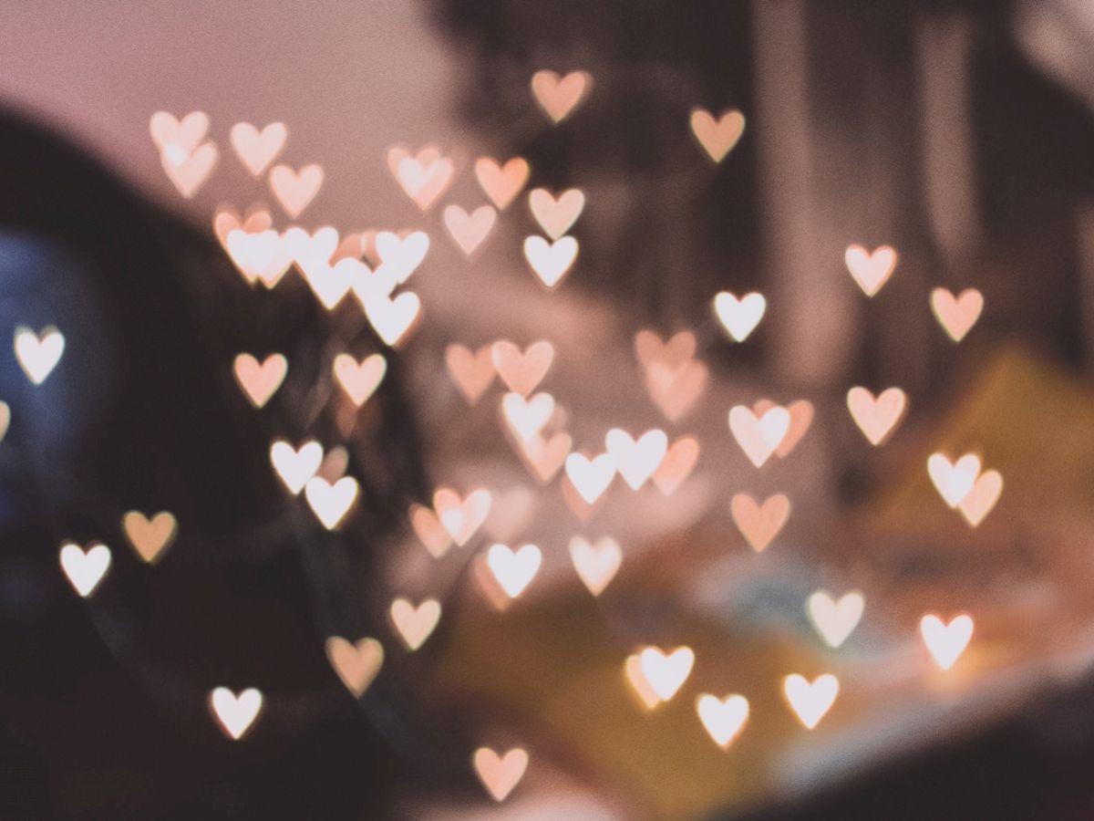 The image shows a blurry background with many small, heart-shaped light bokeh effects scattered throughout, creating a dreamy atmosphere.